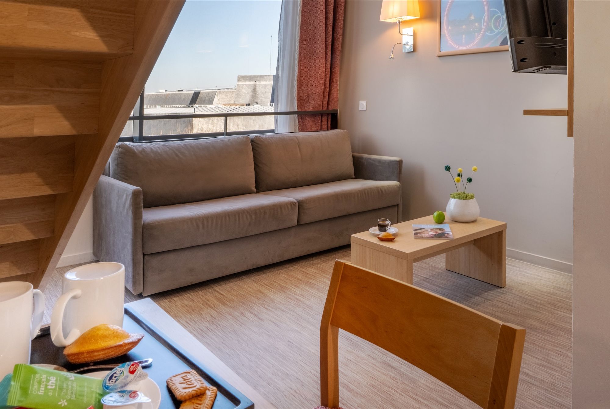 image This inviting space showcases a grey sofa, a wooden coffee table laden with snacks, and a warm atmosphere from the lighting.
