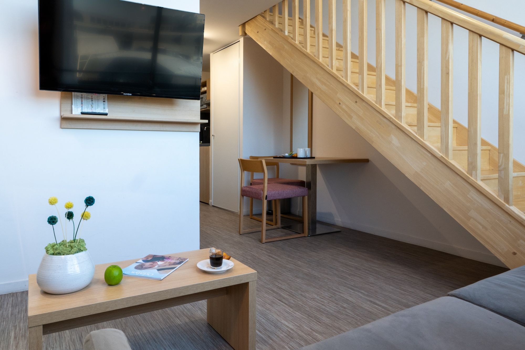image The living area includes a mounted TV and a dining table, highlighted by a staircase leading to additional space.