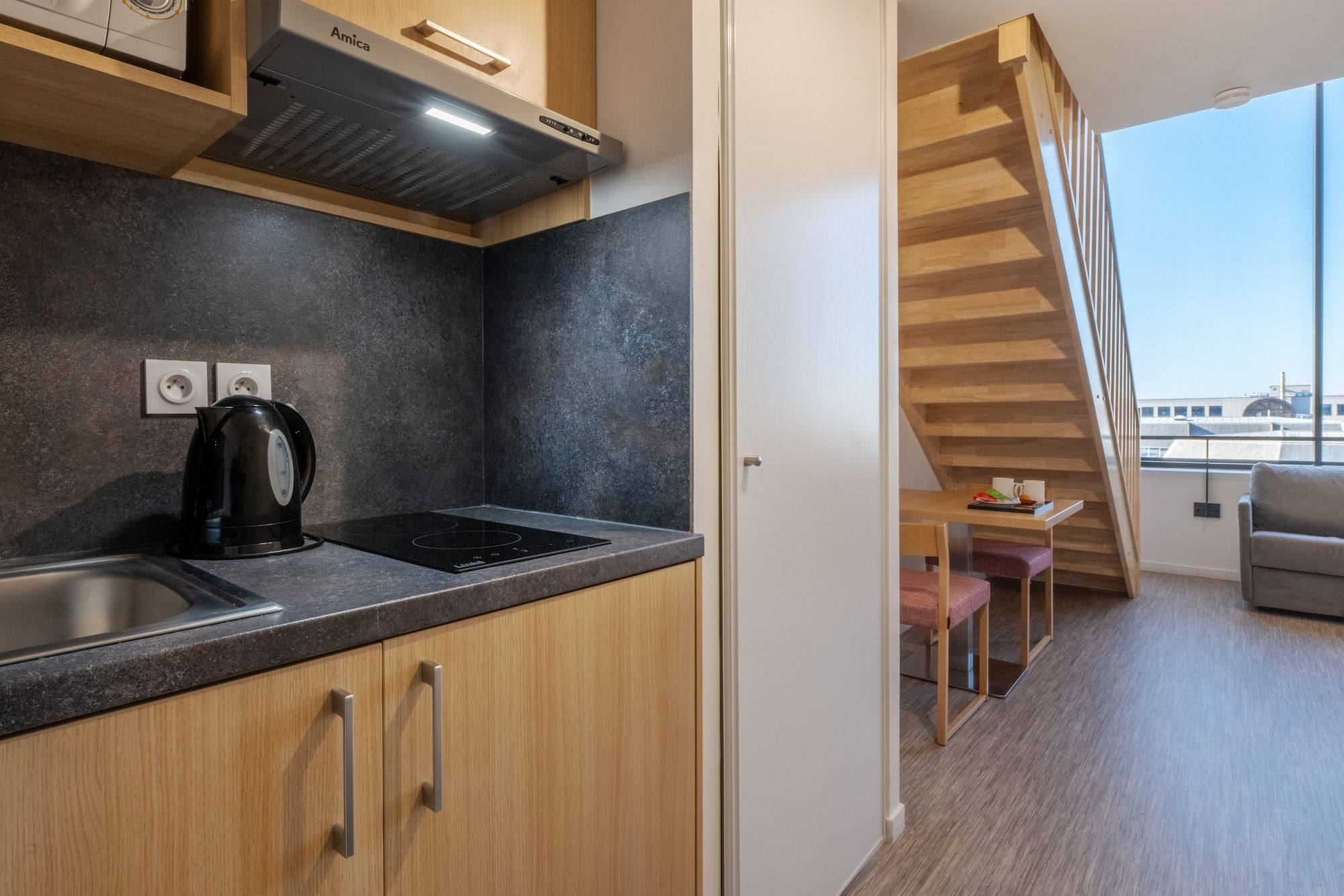 image A well-organized kitchenette with modern appliances seamlessly integrated into a functional living area.