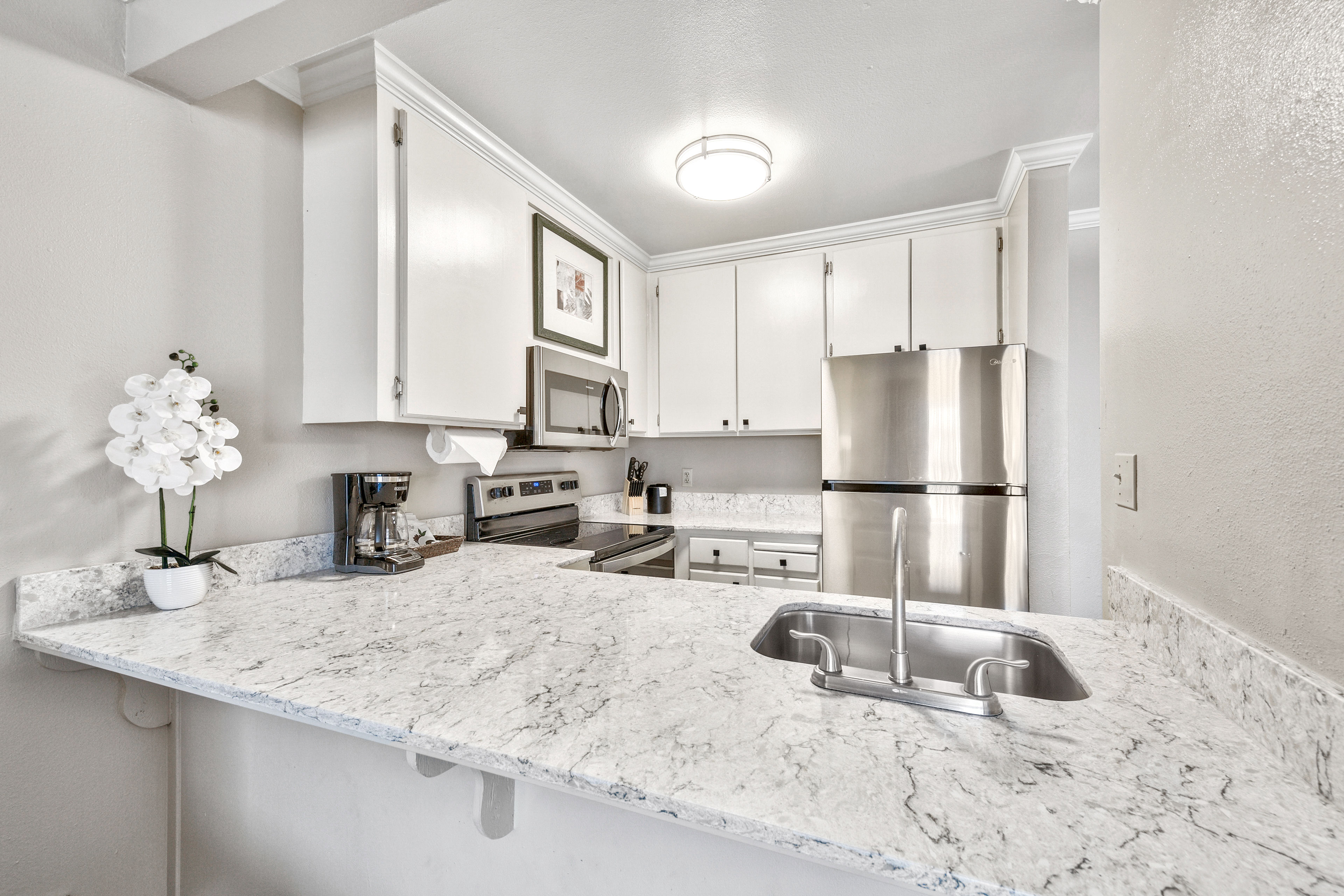 image Sleek countertops and a well-appointed layout make this kitchen a delightful place to enjoy your morning coffee or cook up something special.