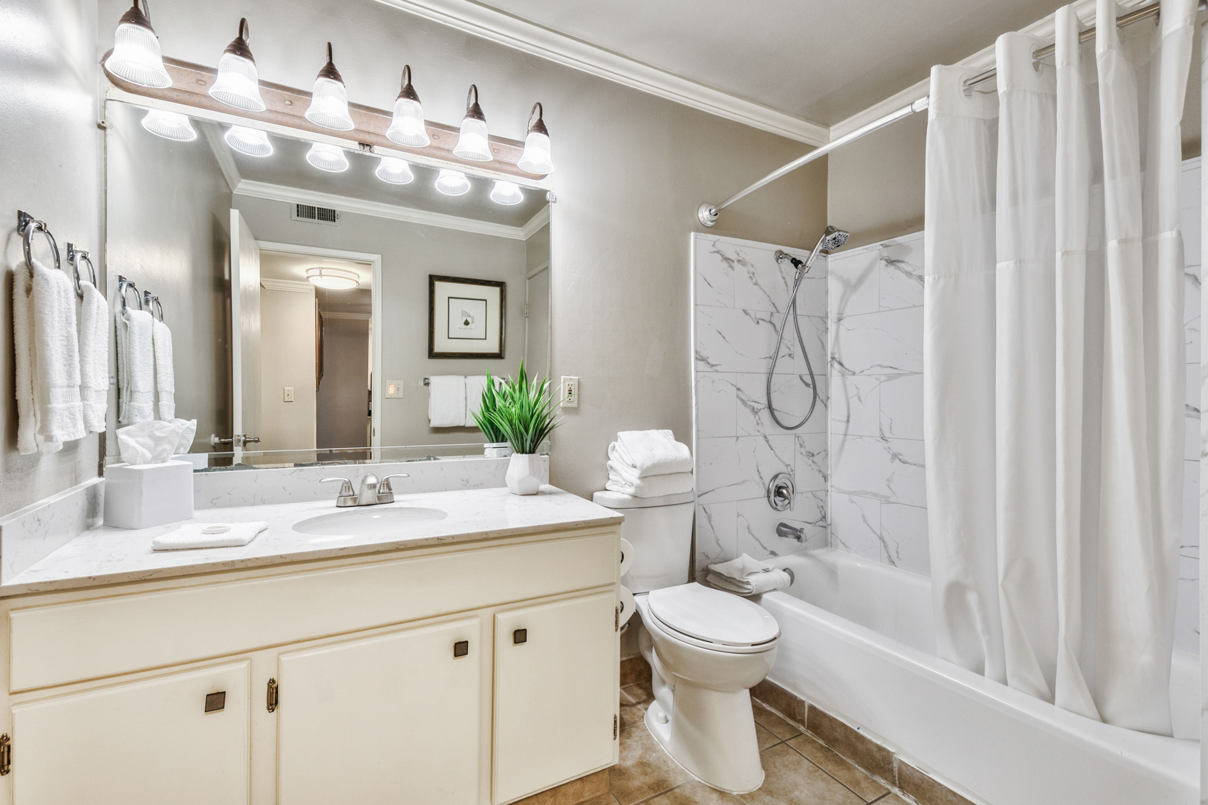 image A bright and spacious bathroom featuring a large vanity, soft lighting, and a relaxing tub-shower combination for ultimate comfort.