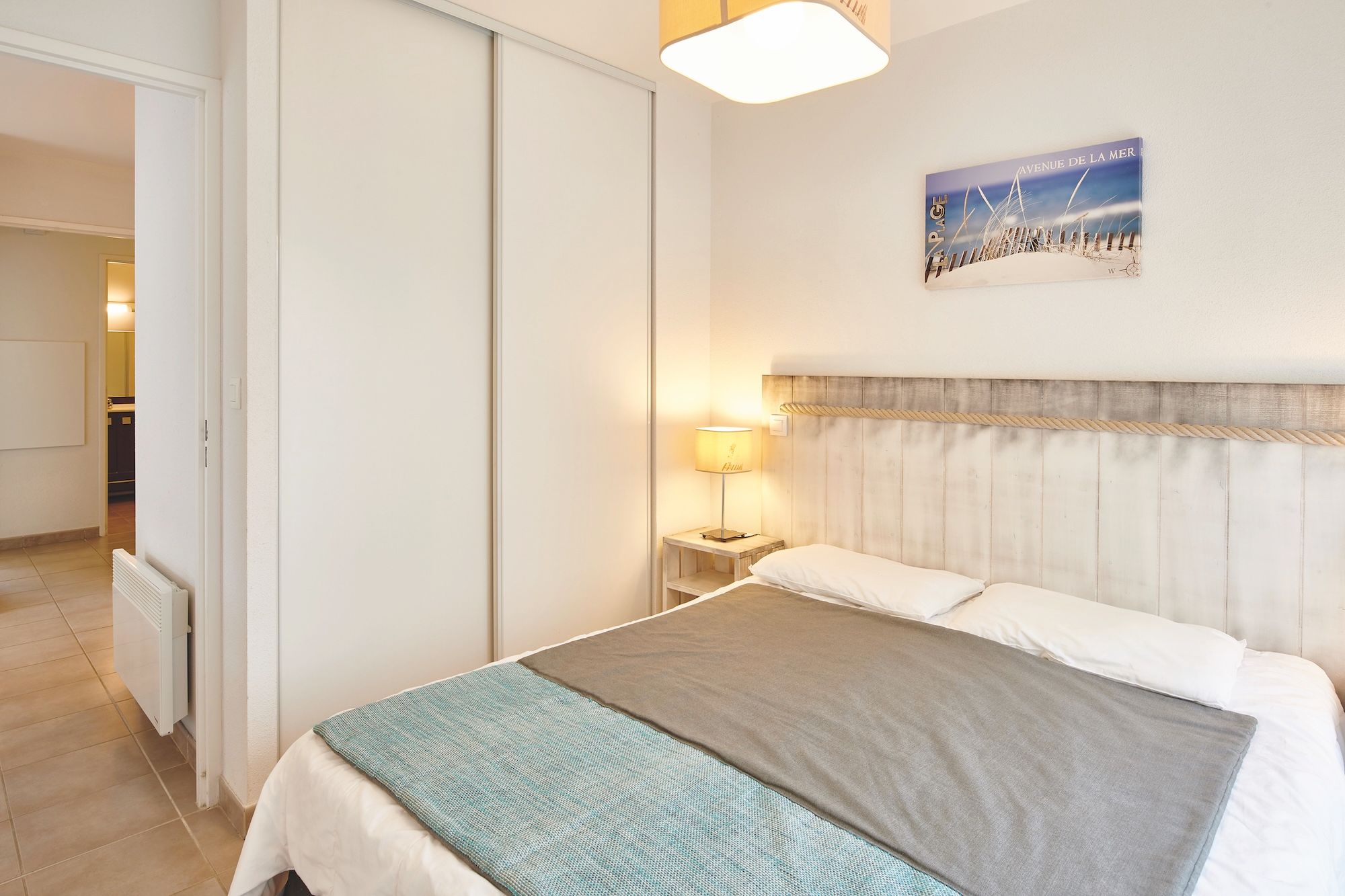 image Sleep in the double bed, with a bedside lamp next to it and sliding wardrobe doors in the background