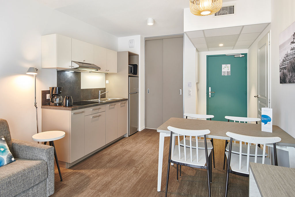 image Cook in the kitchenette while the rest of the group relaxes on the sofa in the same open living area