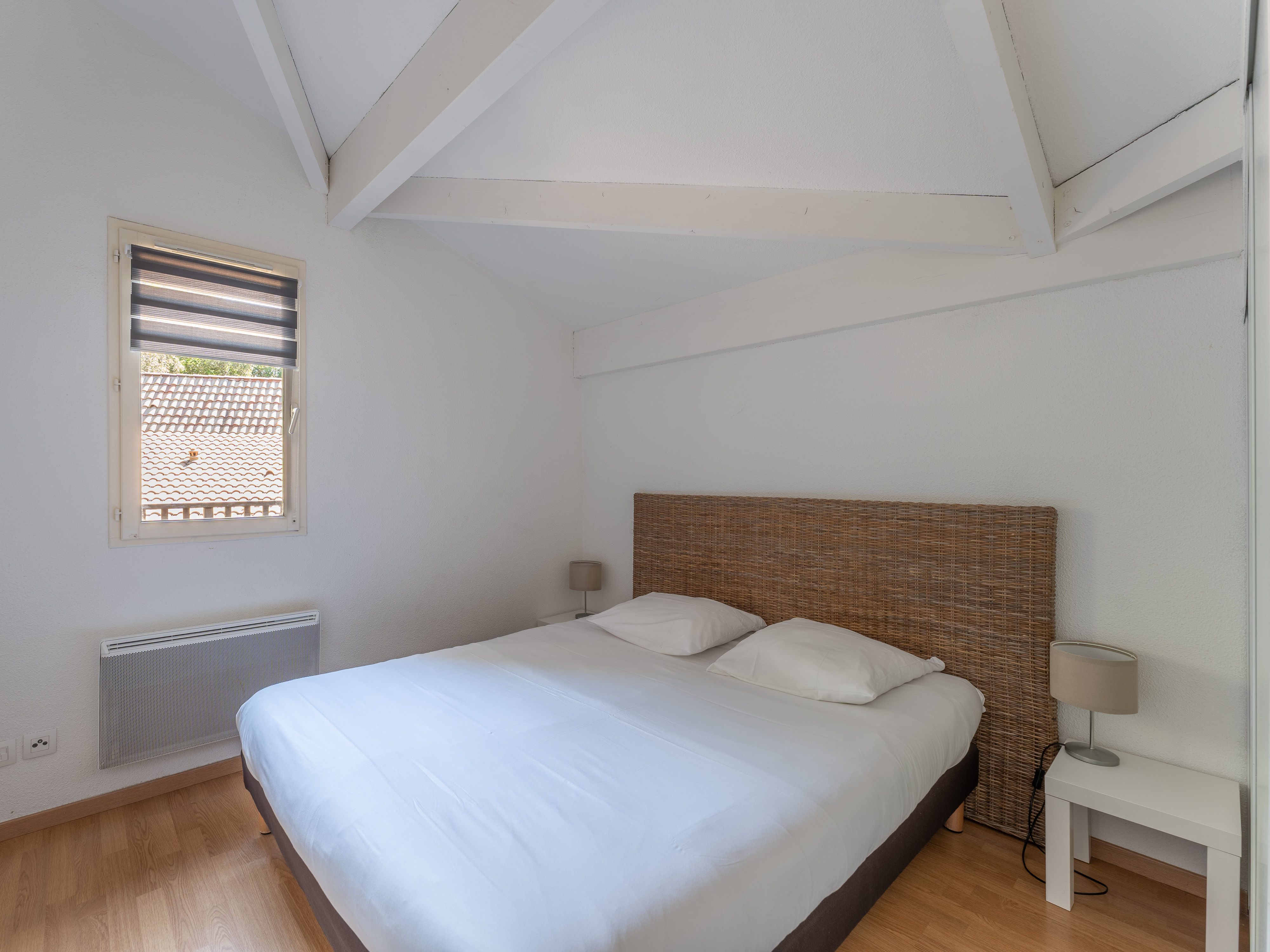 image The restful double bedroom, simply styled with warm timber accents — a quiet retreat after a day cycling the lakeside paths or exploring the Médoc wine country.