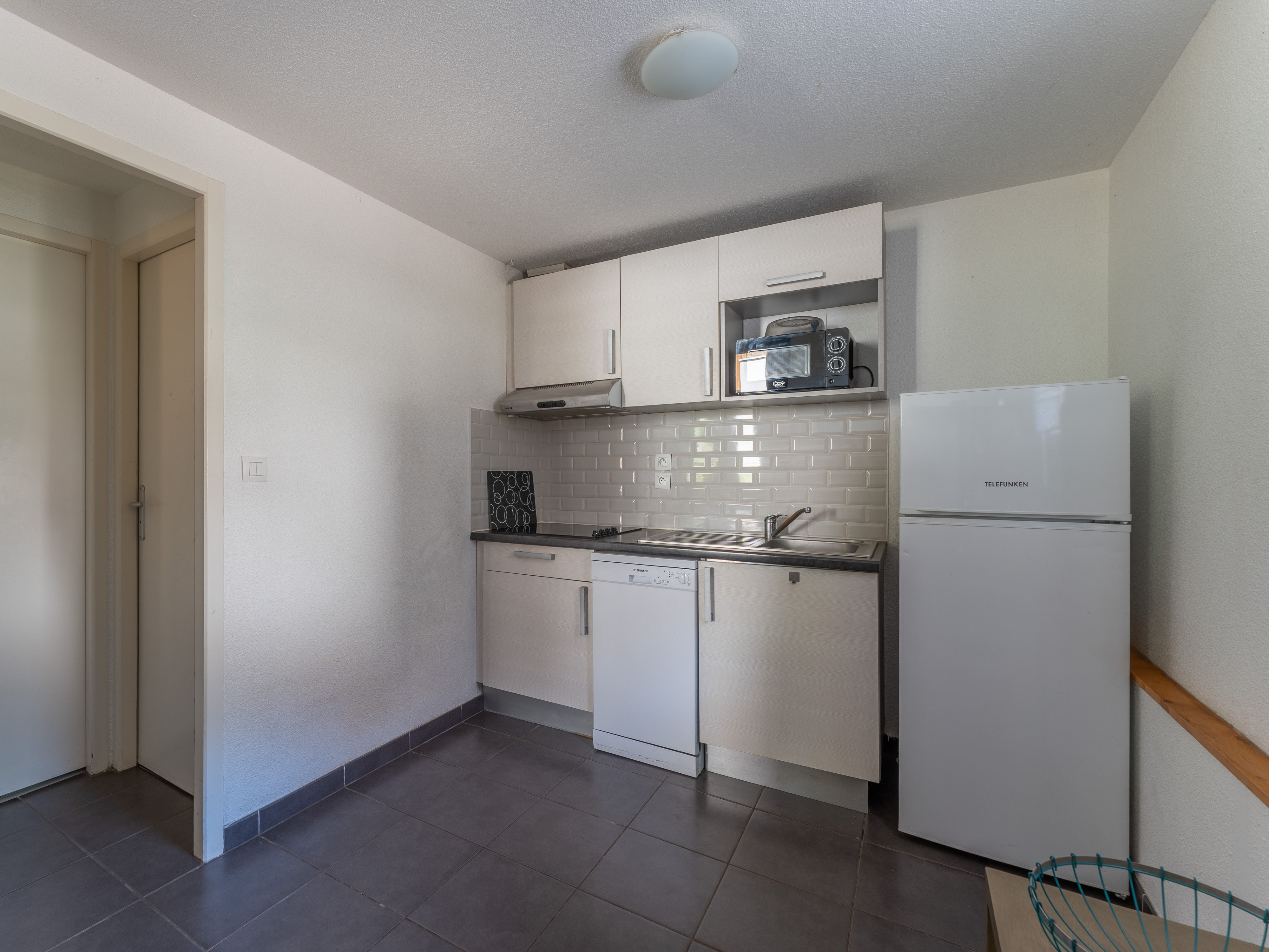 image The well-equipped kitchenette with full-size refrigerator, ceramic hob, microwave and dishwasher — everything in place for relaxed self-catering between days on the lake and the Atlantic coast.