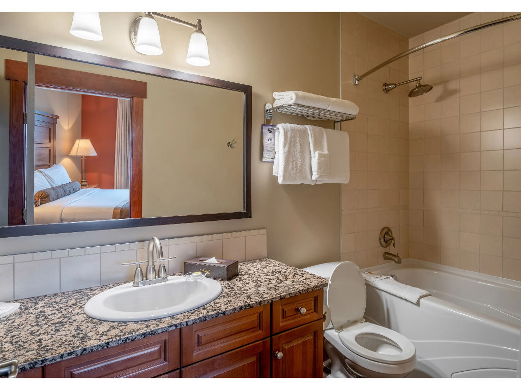 image A spacious bathroom featuring a sleek granite vanity and a deep soaking tub, offering a spa-like retreat after a long day.