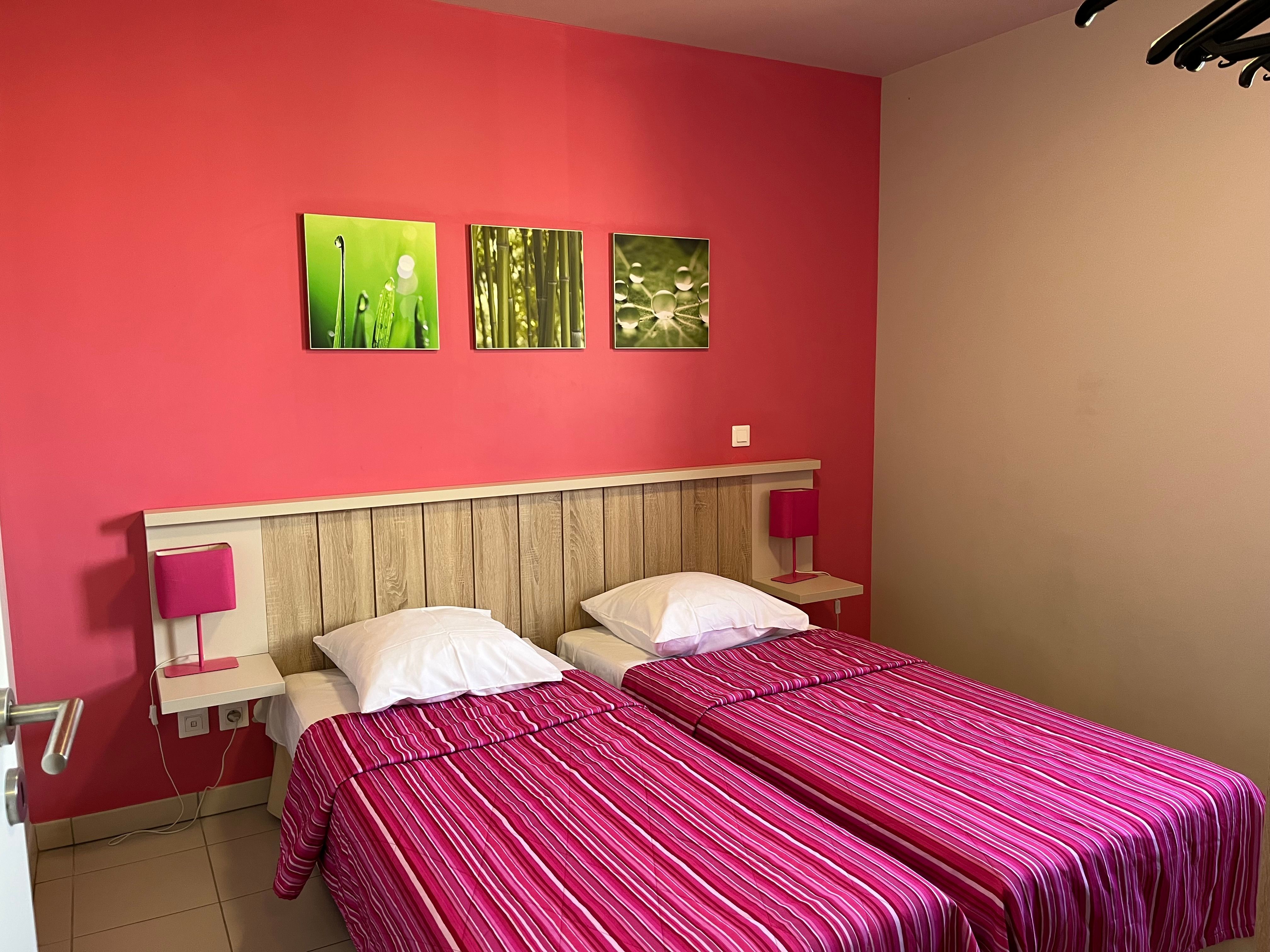 image Bold red walls and striped bedspreads give the second bedroom its own personality — twin beds work well for kids or friends.