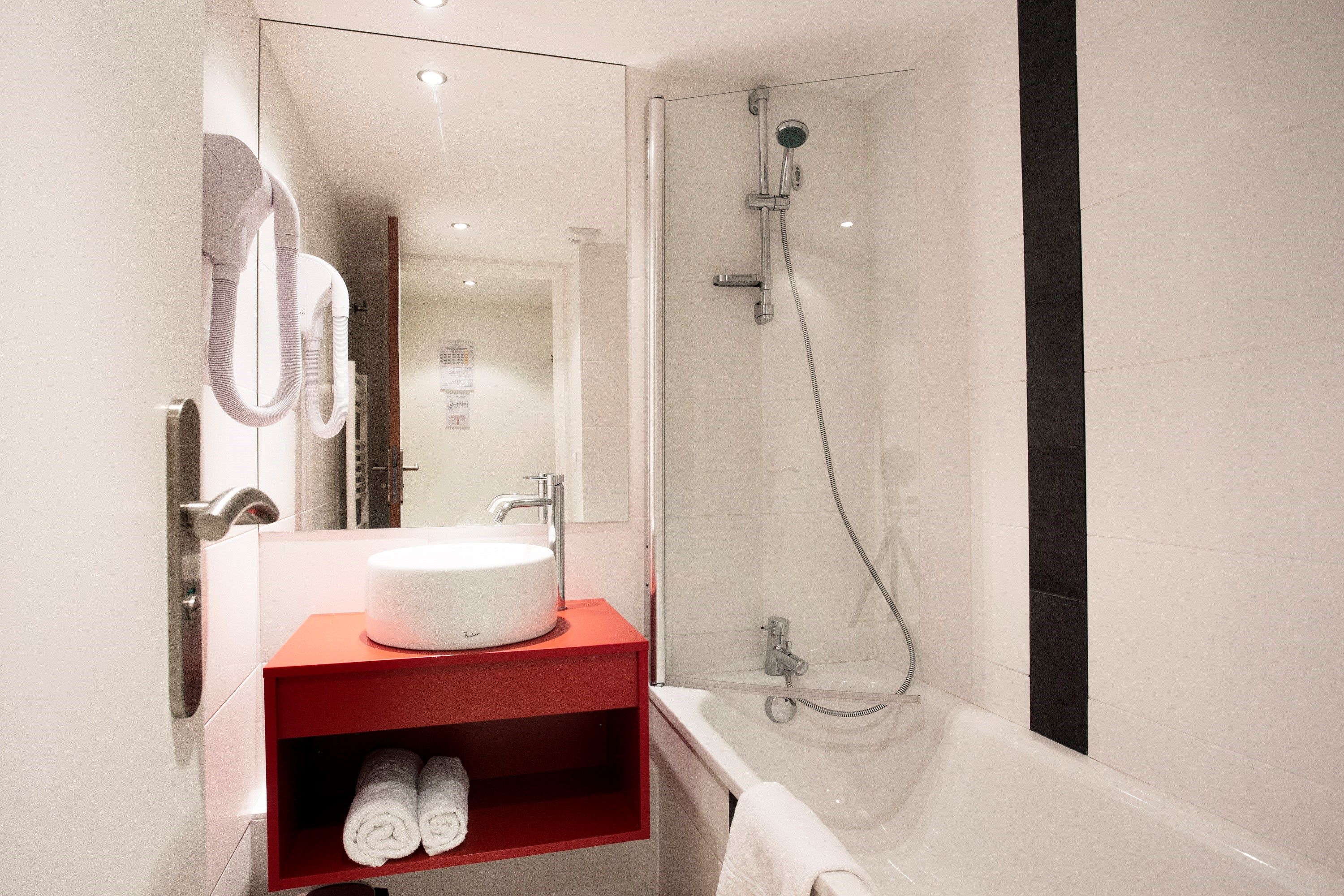image There's a bathroom with a bath or shower and a hair dryer.