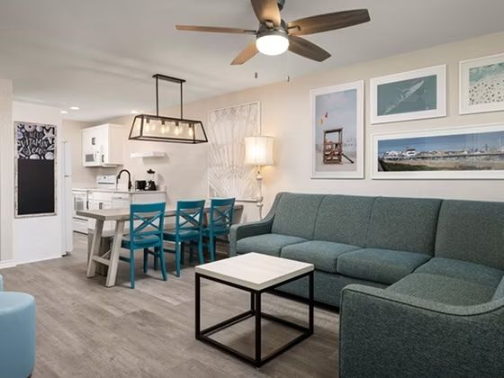 image Teal sectional sofa and dining table with blue chairs in the open living area — coastal wall art throughout