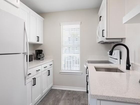 image Bright kitchen with white cabinetry, full-size appliances, and plenty of counter space for cooking