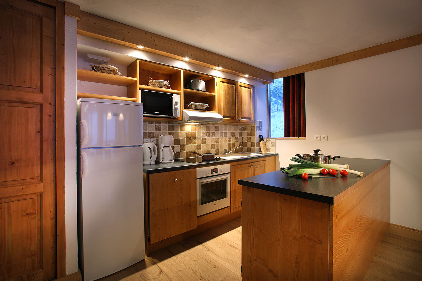 image Equipped kitchen with stove, microwave, kettle and fridge.