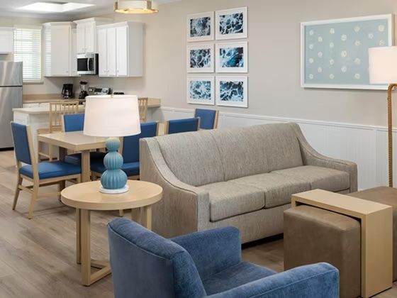 image Beige sofa and blue armchairs in the open living area with dining table and blue chairs — artwork on the walls