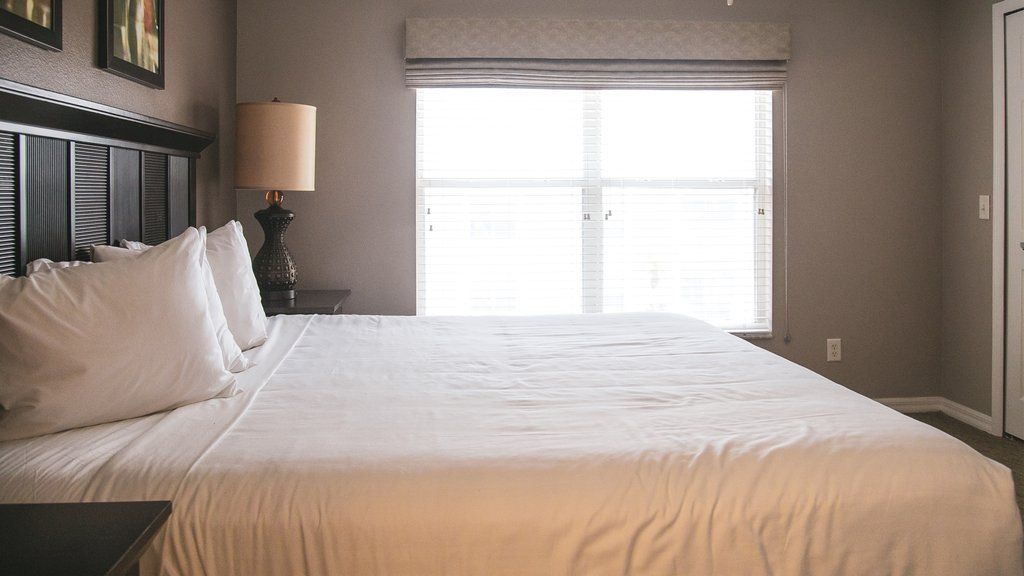 image Unwind in this serene bedroom featuring ample space and natural light, providing a peaceful sanctuary for rest and relaxation, a perfect retreat after a day of excitement at Orlando's theme parks.