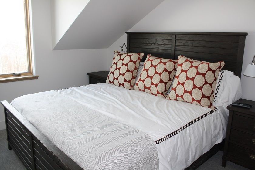 image Relax in the comfortable bedroom featuring a plush bed with patterned accent pillows and warm natural light.