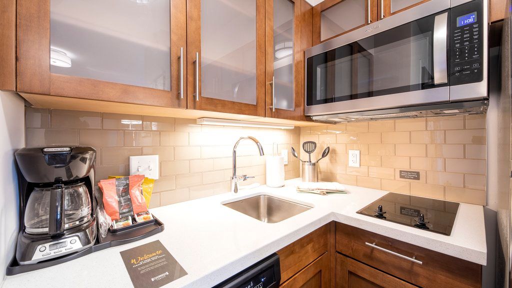 image The kitchenette is equipped with a coffee maker, microwave, and sink, featuring wooden cabinets and modern appliances.