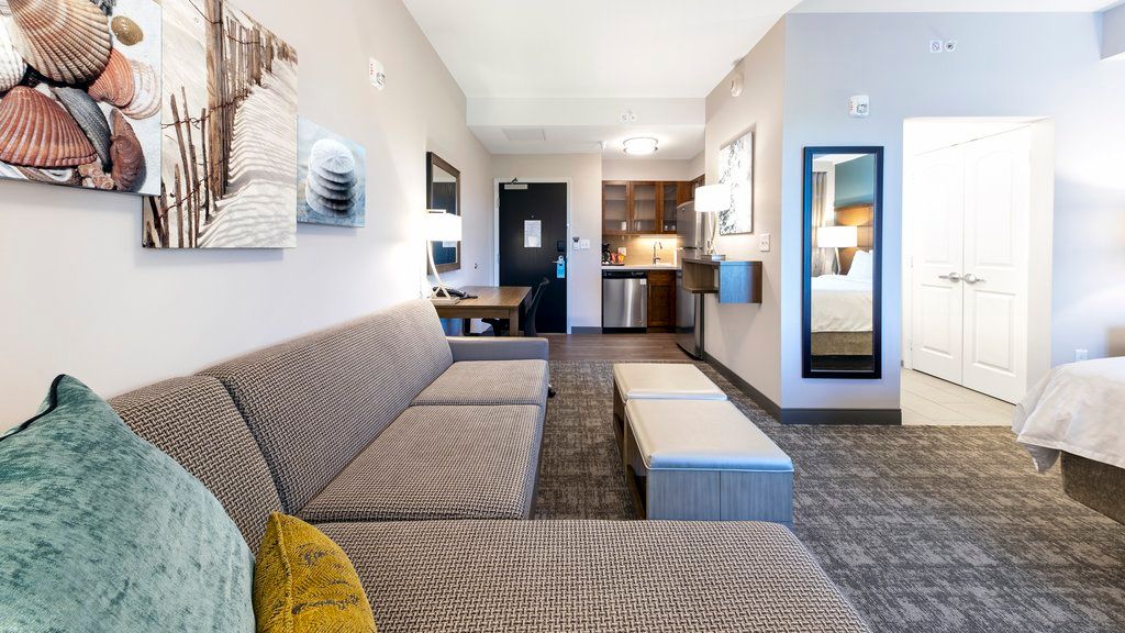 image Relax in a studio featuring a sofa, ottoman, table, kitchenette, and decorative artwork on the walls.