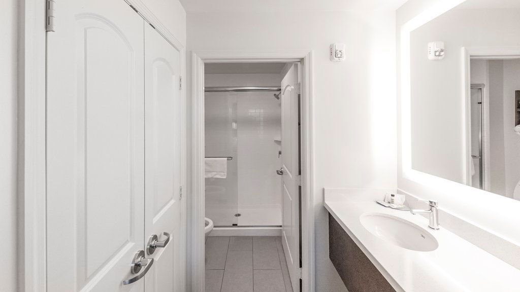 image The bathroom includes a white sink, wall-mounted mirror, and a shower enclosure visible through an open door.