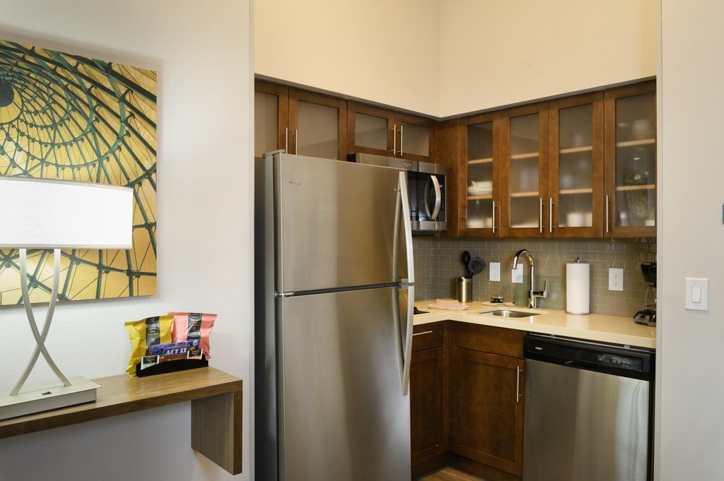 image The kitchen features stainless steel appliances, including a refrigerator and dishwasher, paired with sleek wooden cabinetry.