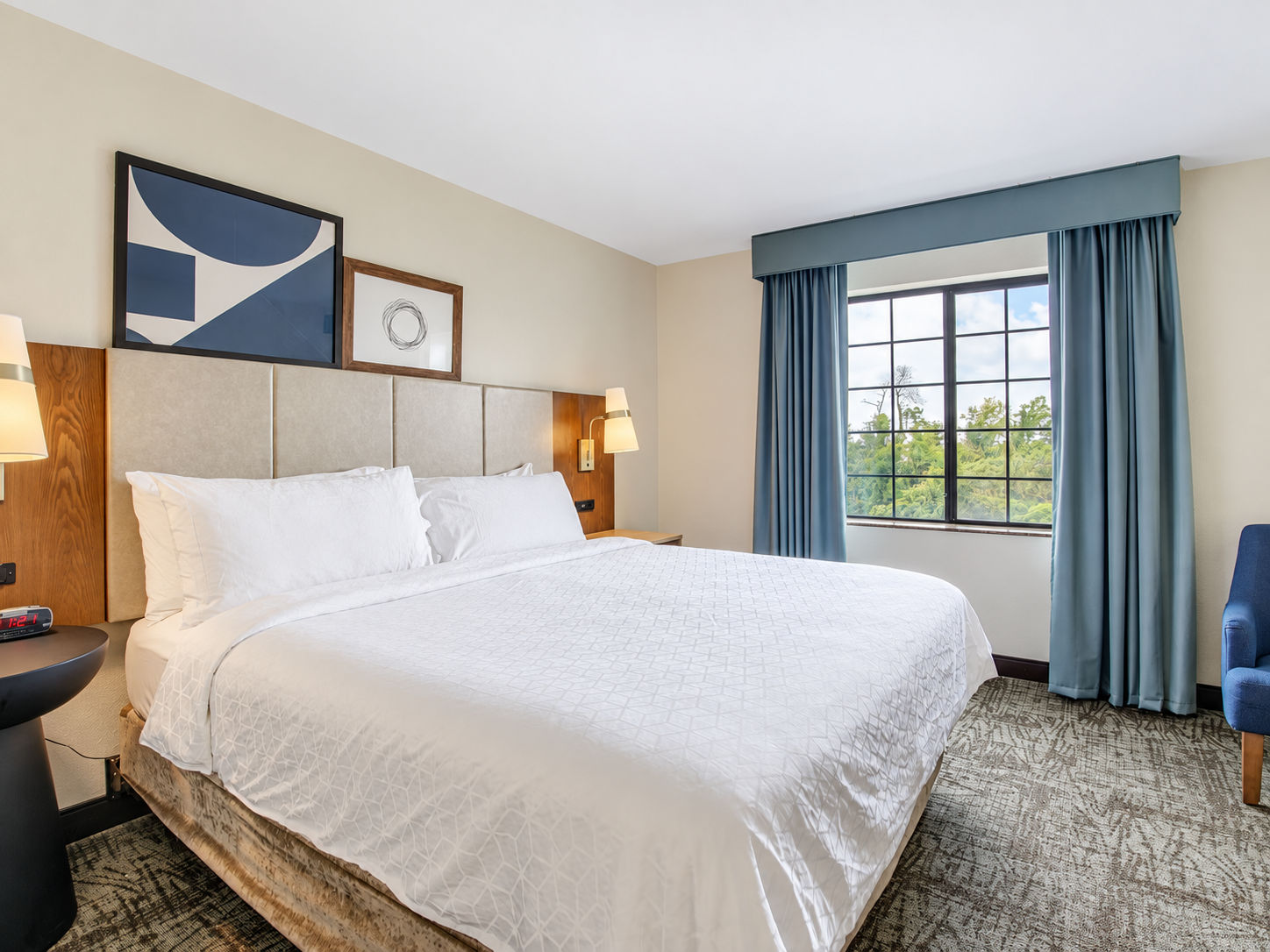 image Bright studio with a queen bed, bedside lamp, and a window with drape curtains