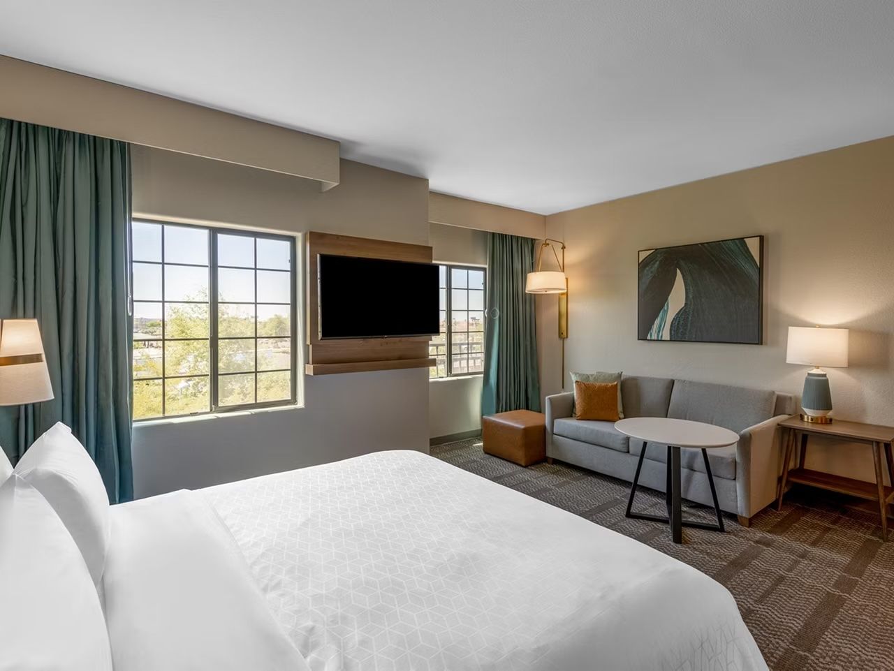image King bed and pull-out sofa in an open studio layout with large windows and a mounted TV