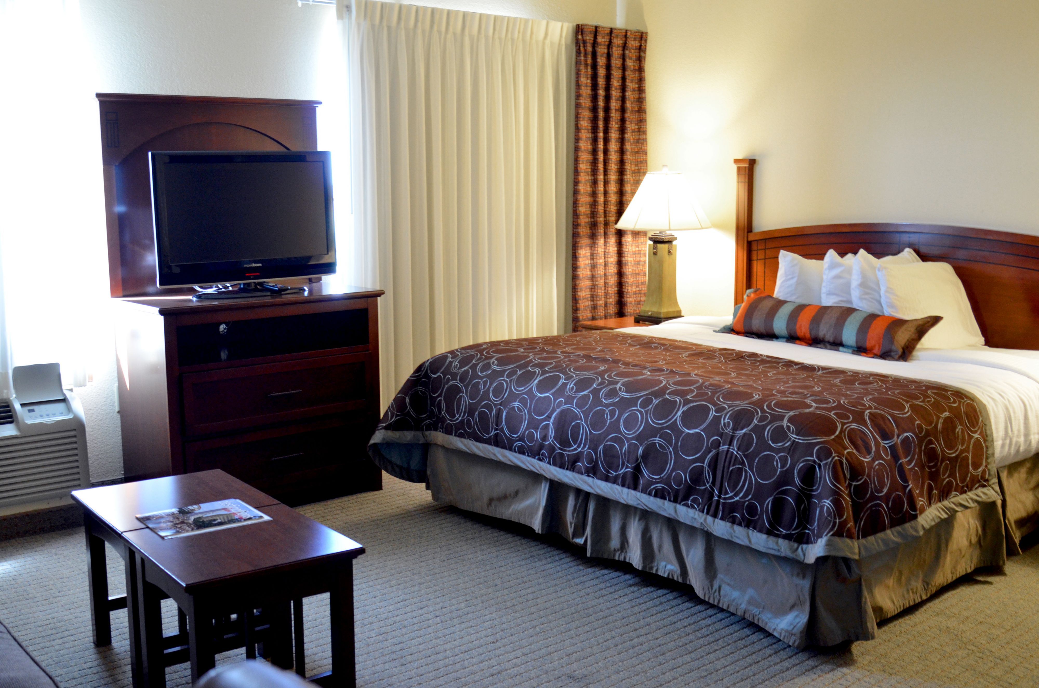 image Cozy bedroom featuring a comfortable bed and large flat-screen TV.
