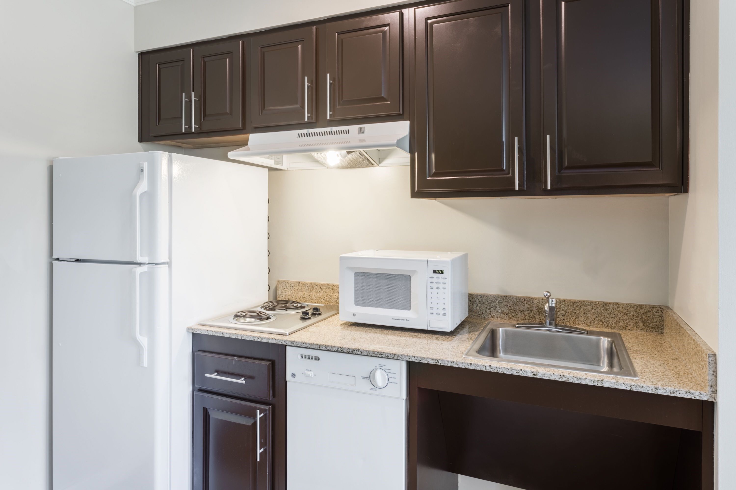 image Fully equipped kitchen with refrigerator, microwave, cooktop, and counter seating.