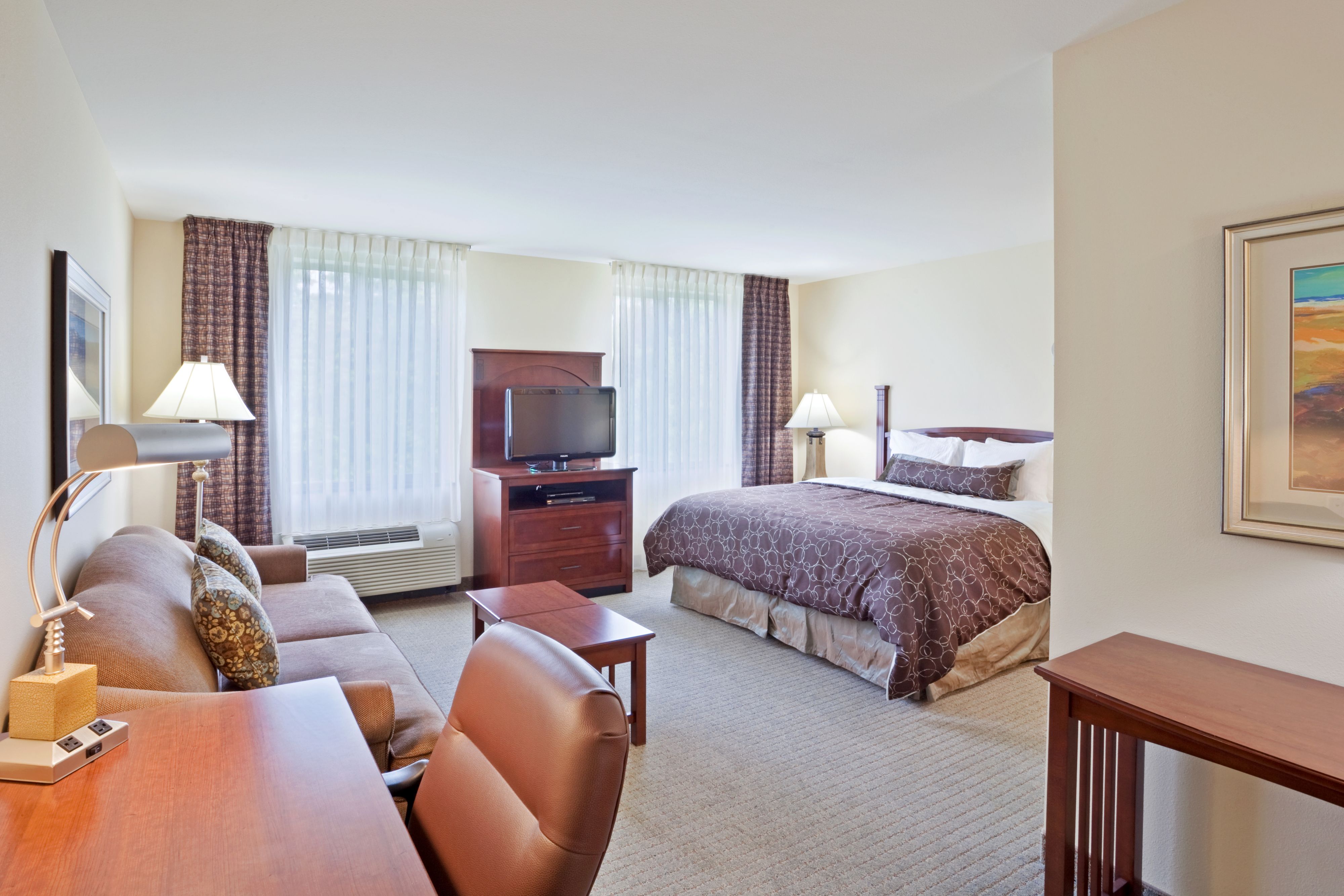 image Spacious room with a sofa, desk, and bed.