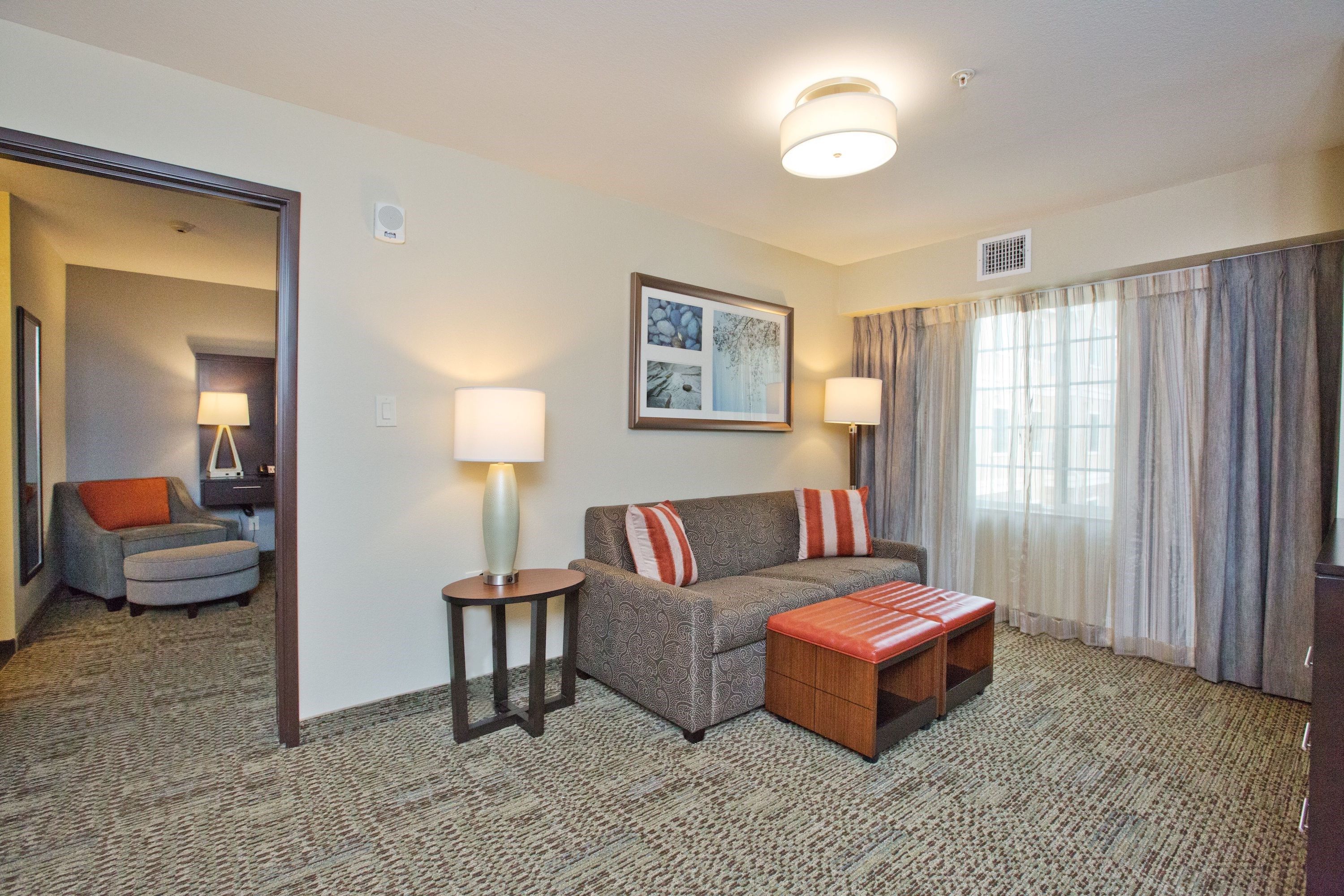 image Living area with sofa, decorative pillows, coffee table, and large windows.