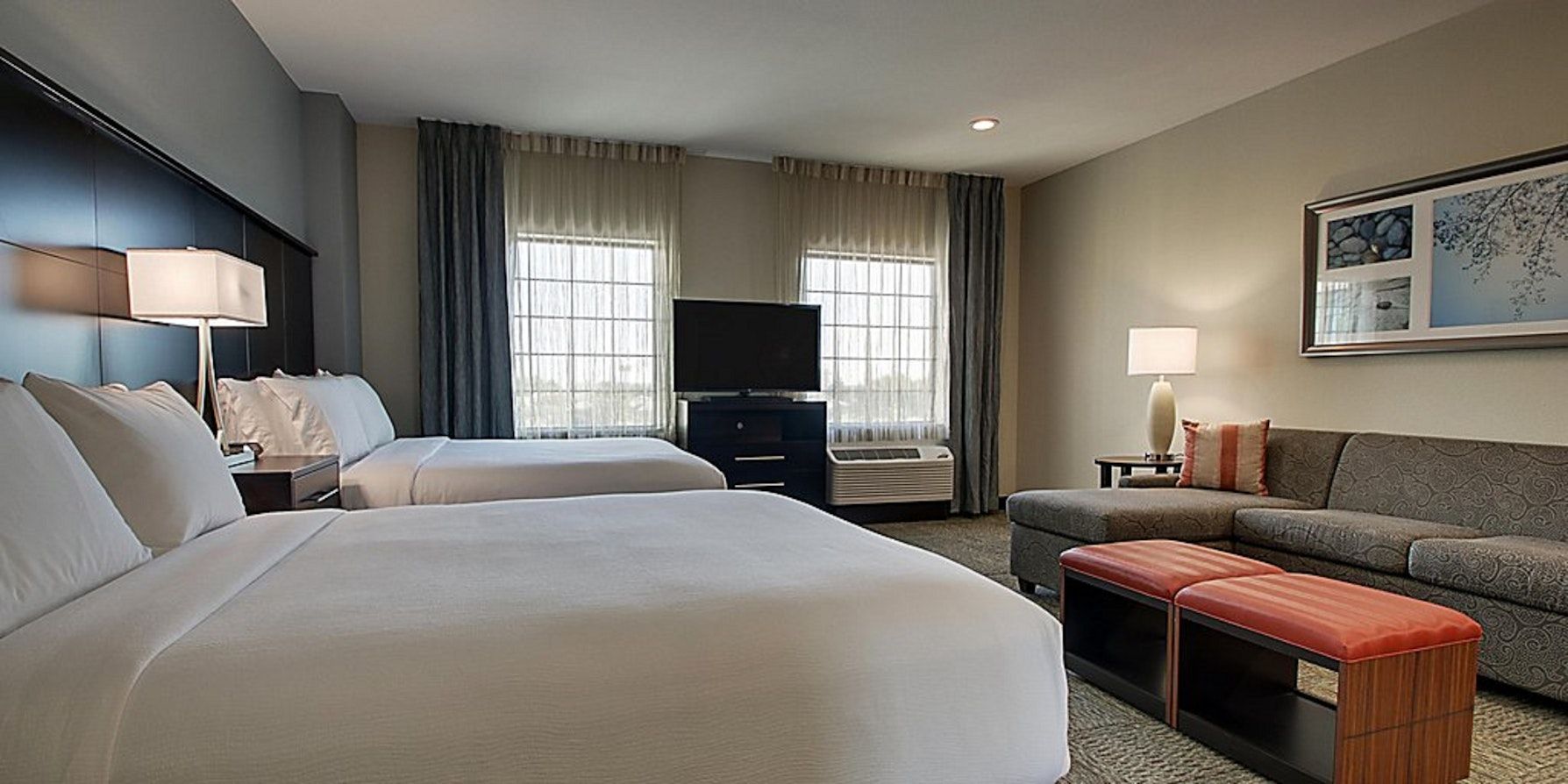 image Unwind with comfort in this spacious room, equipped with plush bedding, a TV, and a comfortable seating area.