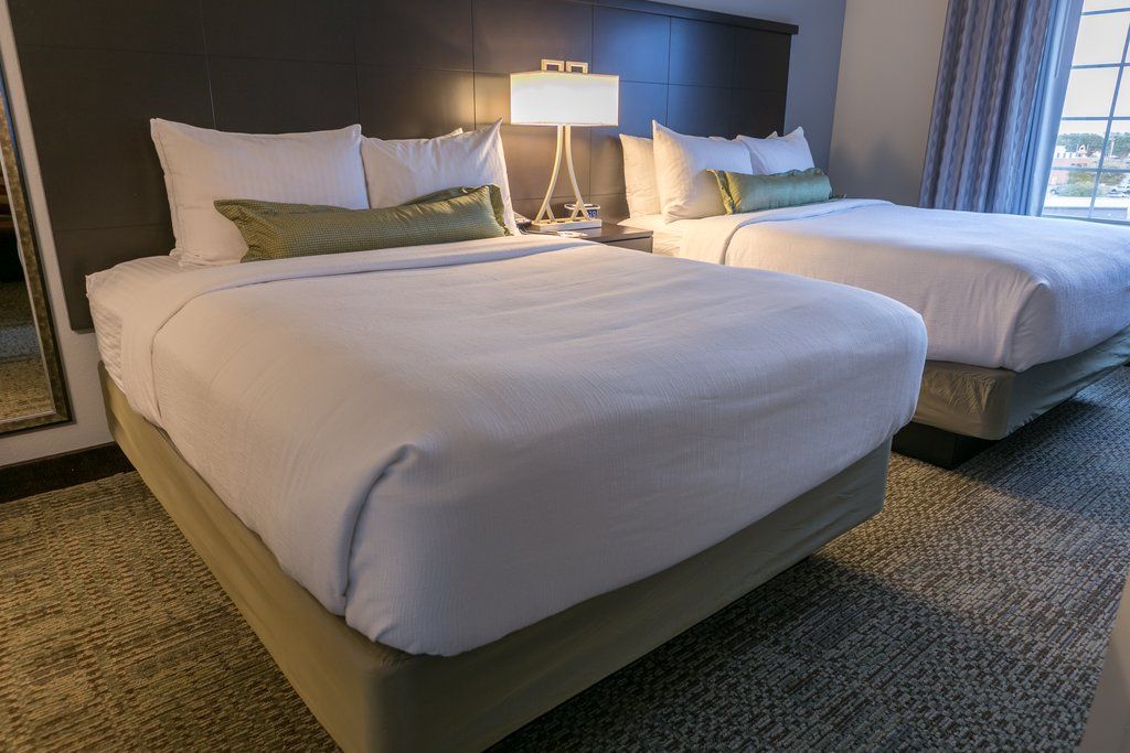 image Drift off to sleep in this inviting bedroom, highlighted by two luxurious queen beds and soft linens, creating a peaceful retreat after a long day.