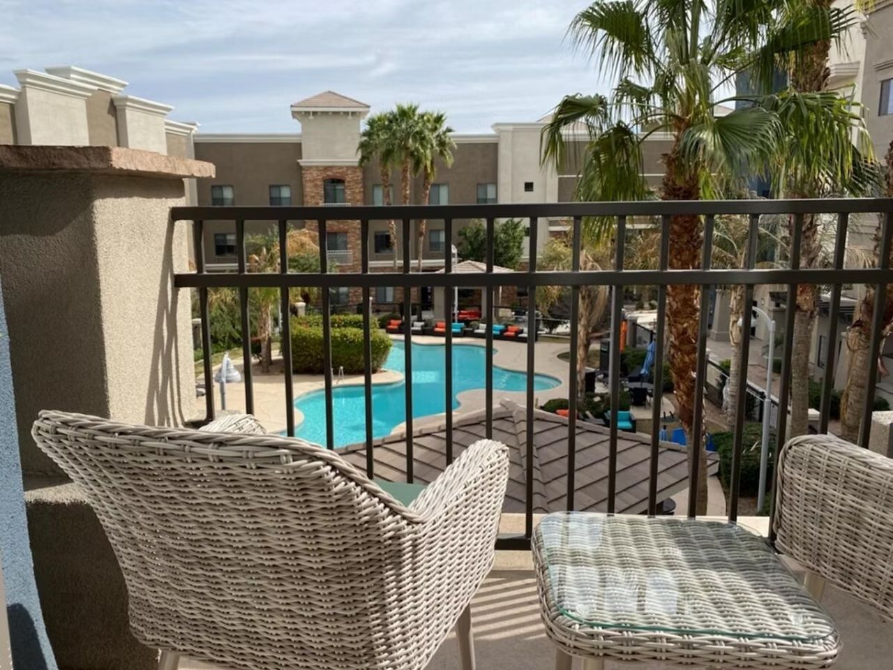 image Private balcony with two wicker chairs overlooking the pool and palm courtyard