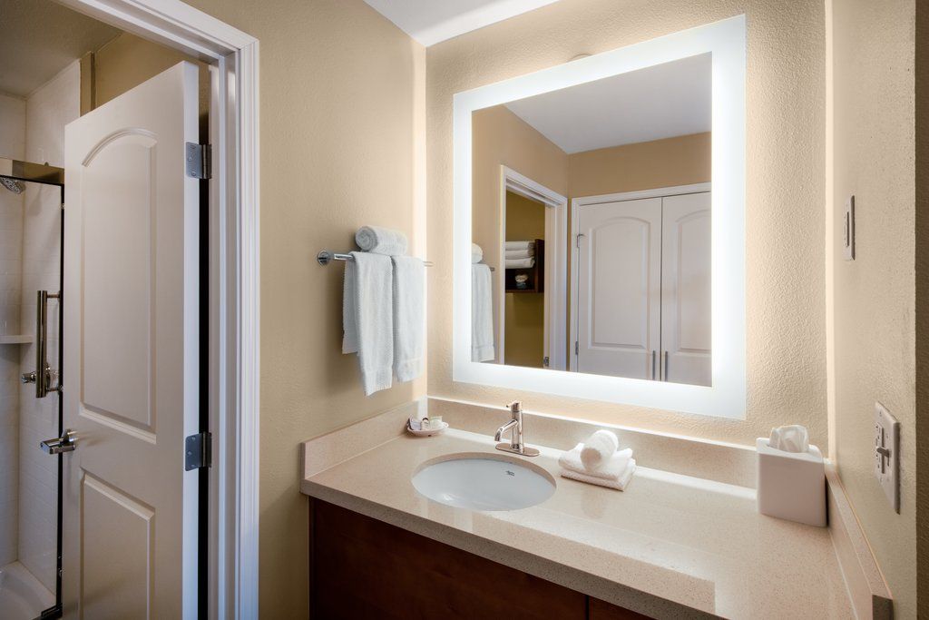 image Bright bathroom with a circular sink, illuminated mirror, and a glass-door shower with accessibility grab bar