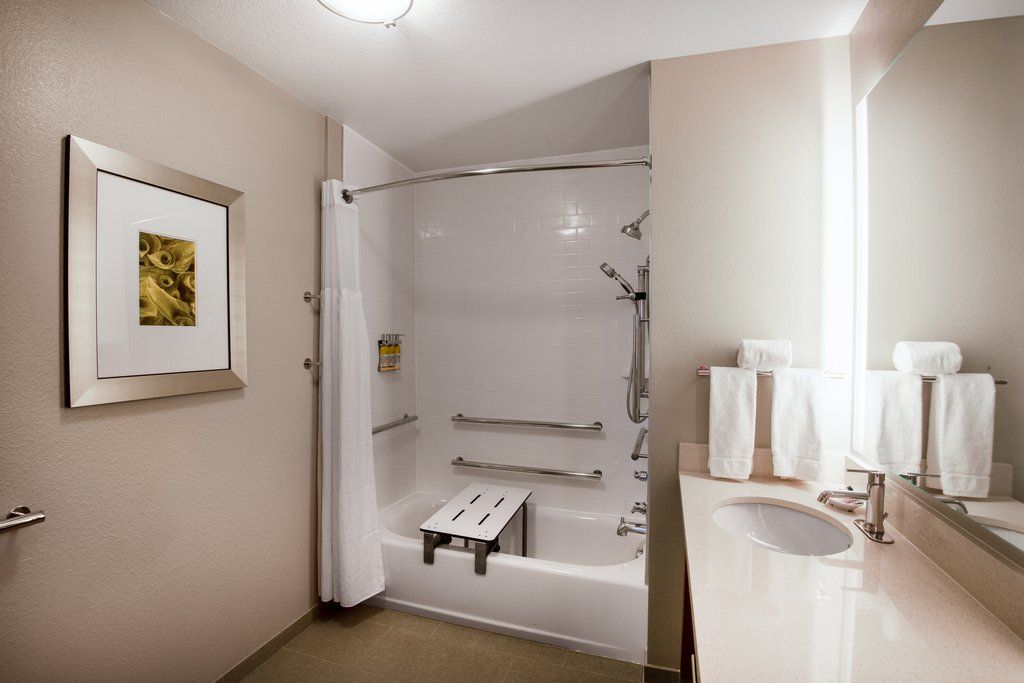 image Mobility-accessible bathroom with tub, built-in grab bars, and a clean vanity with towels provided