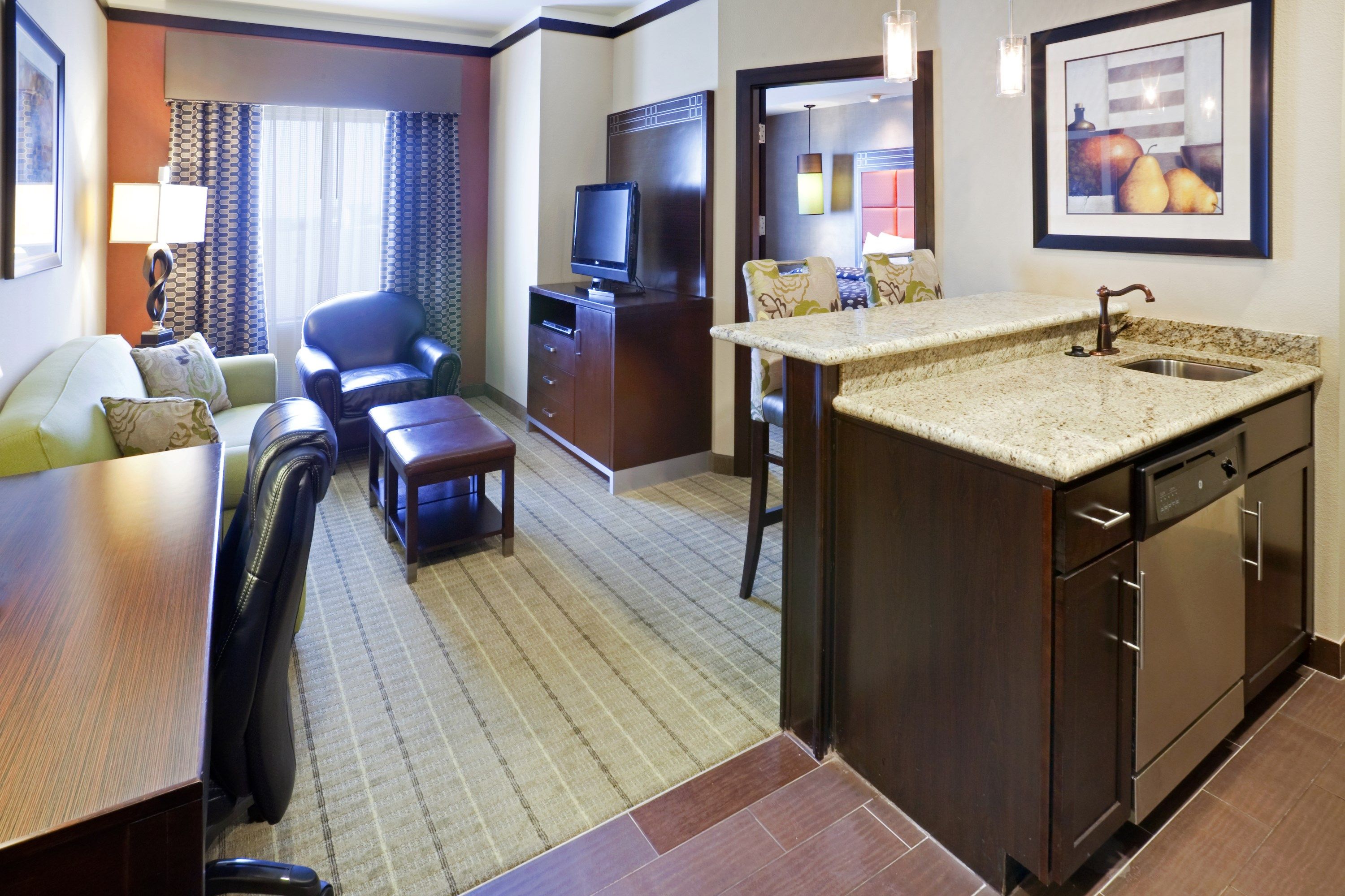 image Living area with kitchen, sofa, chairs, and TV.