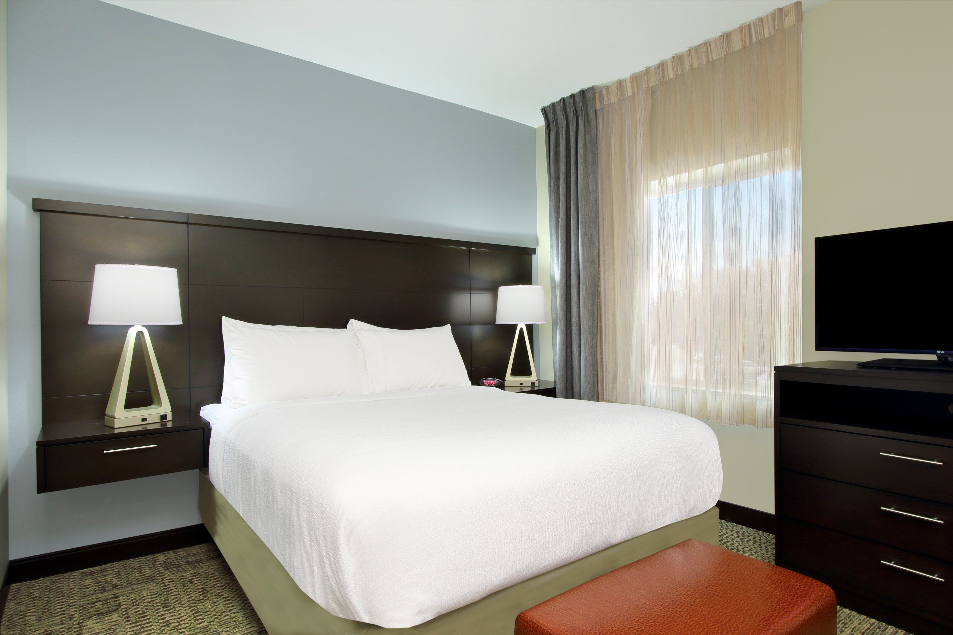 image Studio living area with queen bed, work desk, and flat-screen TV — functional and comfortable for longer visits
