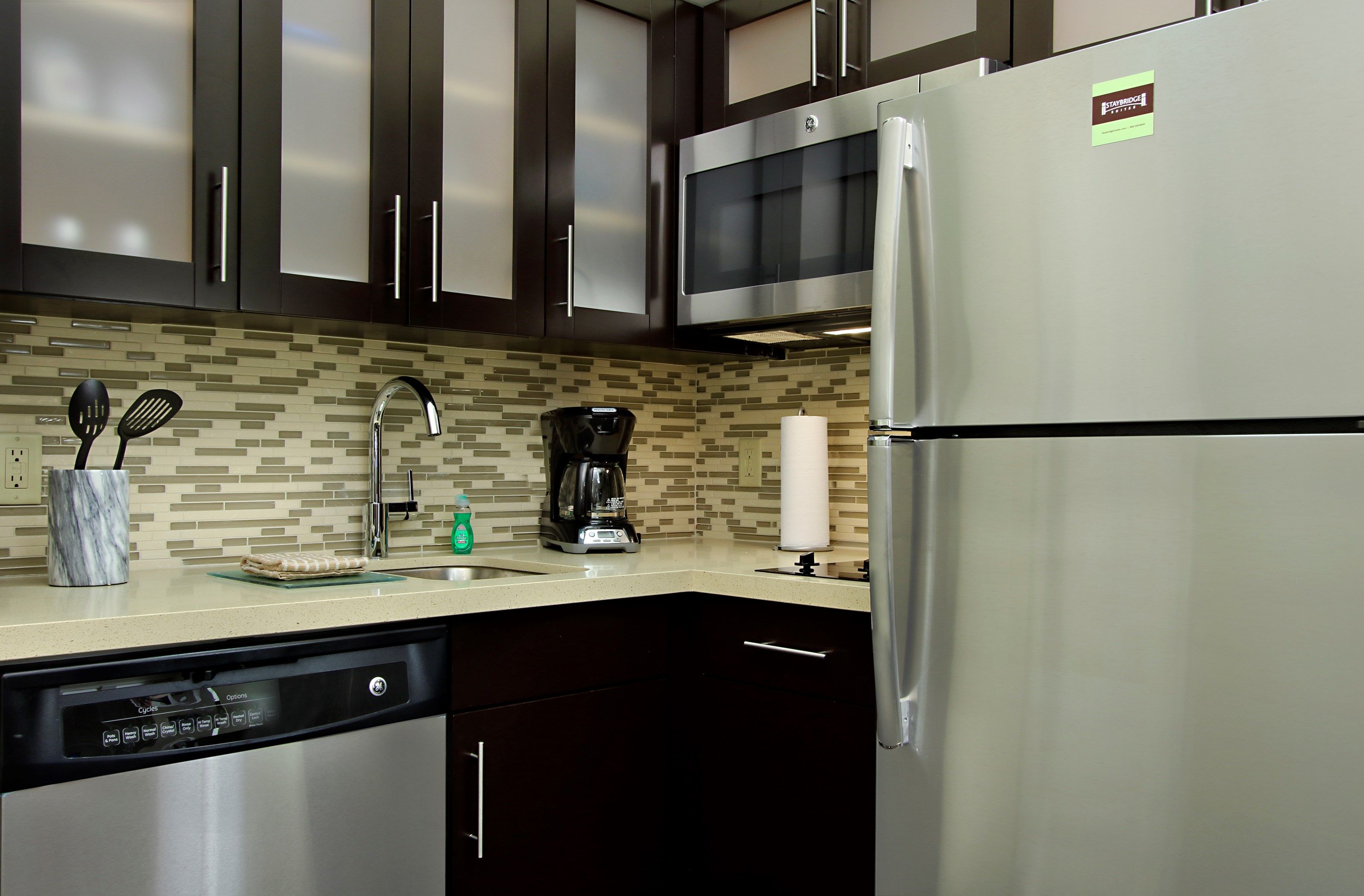 image Modern kitchen with stainless appliances, tile accents, stovetop, microwave, and dishwasher — meals made easy