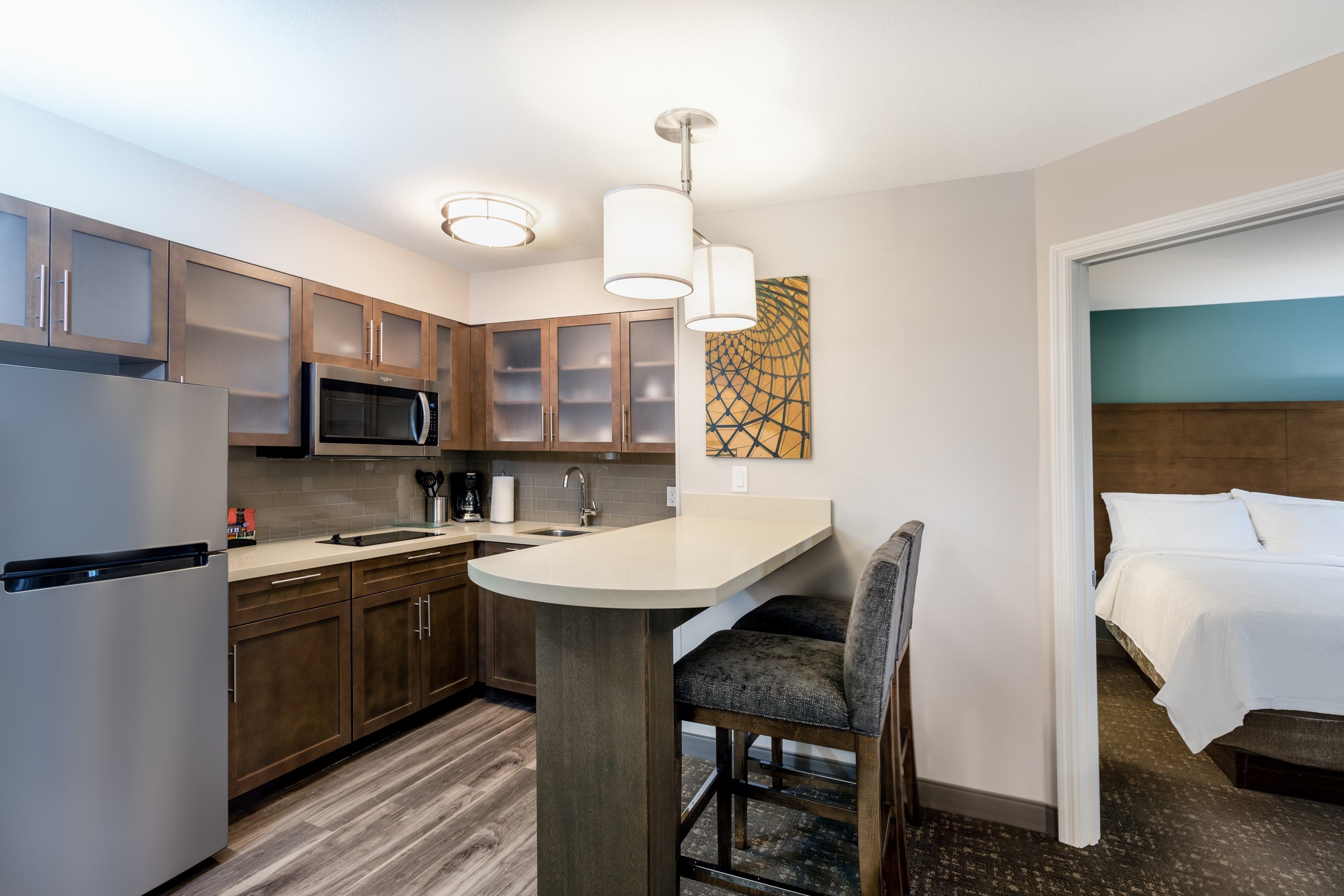 image Cook in the full kitchen with stainless appliances, stovetop, dishwasher, and a bar counter that seats two