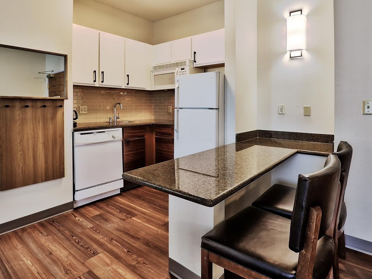 image Bright kitchen with sleek countertops, full stove, microwave, dishwasher, refrigerator, and a dining bar that seats 2