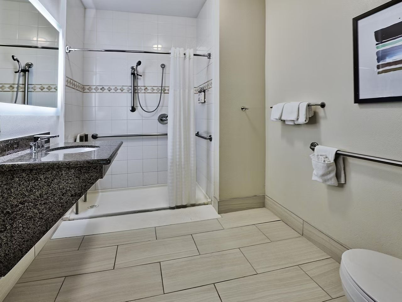 image Accessible bathroom with roll-in shower, grab bars, and modern finishes — hair dryer and complimentary toiletries included