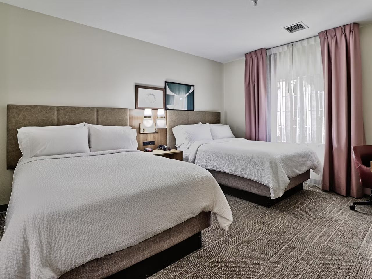 image Second bedroom with two double beds, fresh linens, and a dedicated workspace — visual alarm devices present throughout