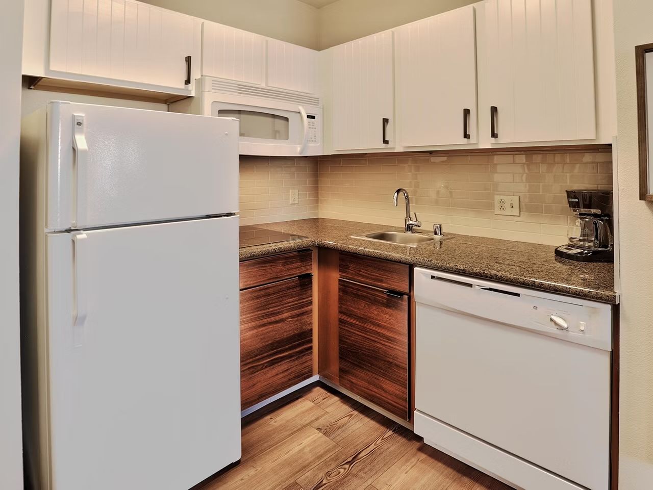 image Modern kitchen with white cabinetry, wood accents, full stove, microwave, dishwasher, and coffee maker