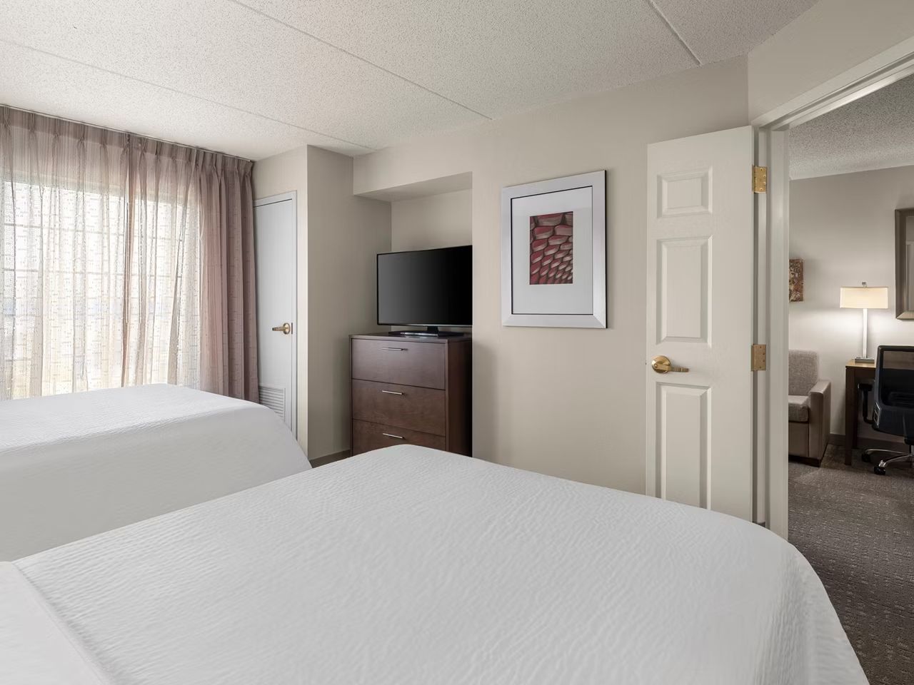 image Bright bedroom with two beds and a TV.