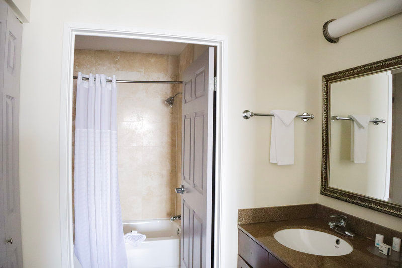 image Bathroom with shower curtain, vanity, mirror, and towel bar.