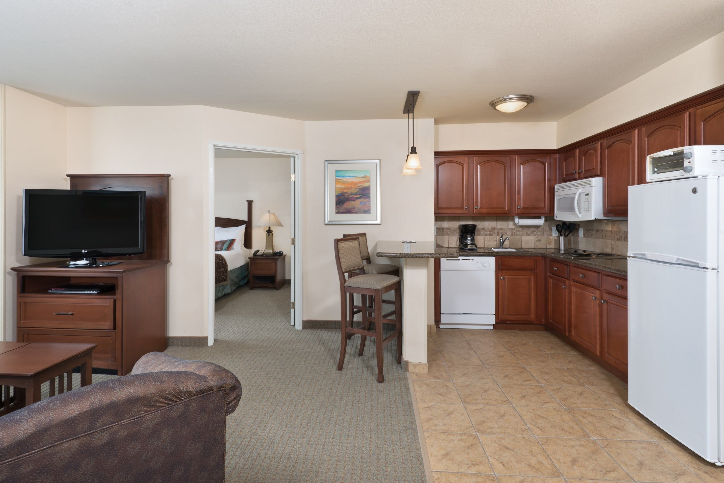 image Open-concept living and kitchen area with sofa, TV, and bar.