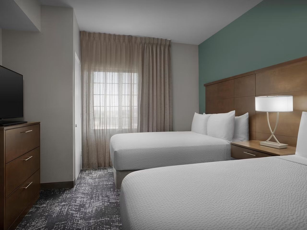 image Bright bedroom with two double beds and flat-screen TV.