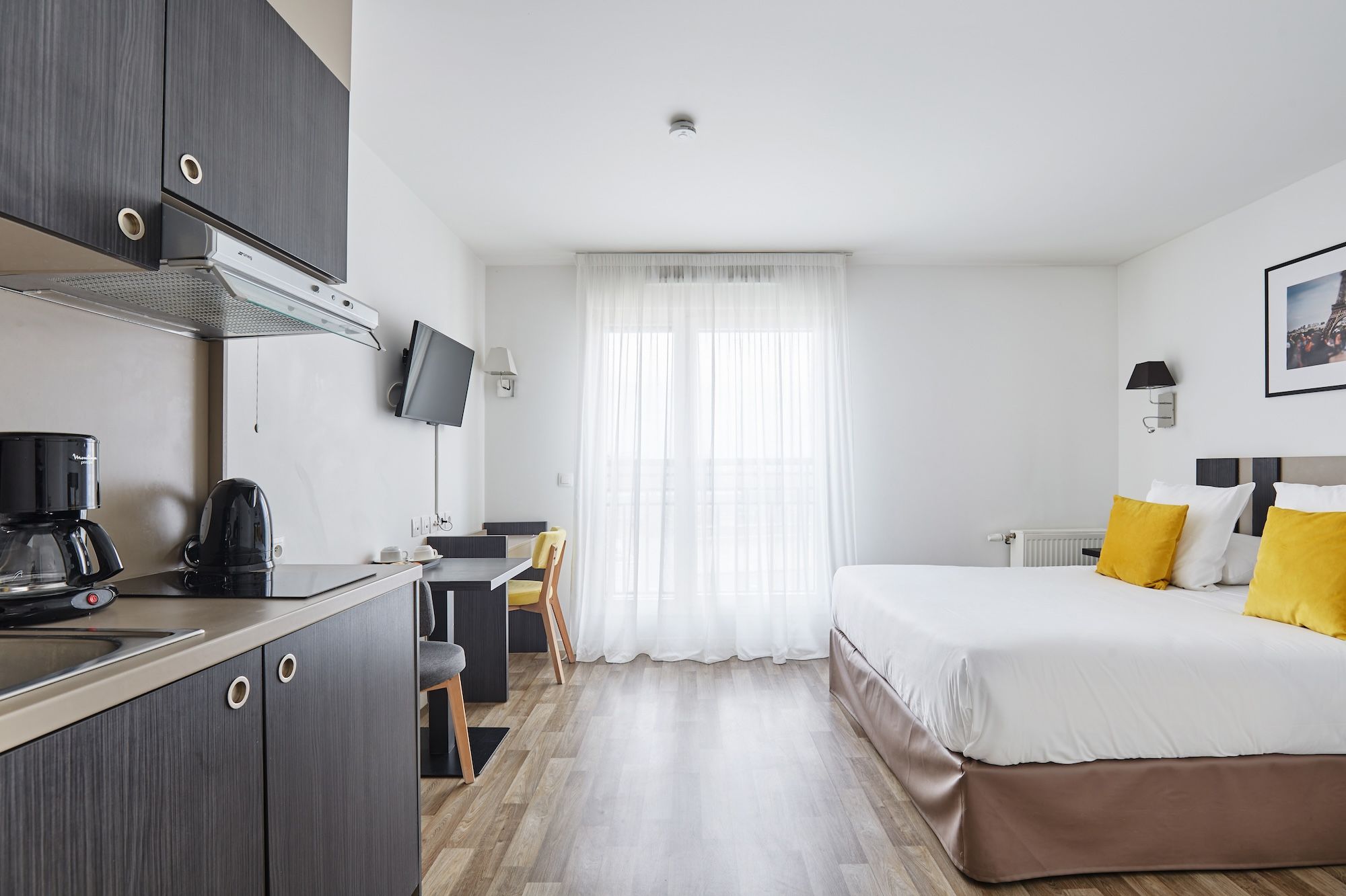 image Experience comfort in the cozy living/sleeping area featuring a flexible double or twin bed setup, complemented by a well-equipped kitchenette and a bright ambiance.