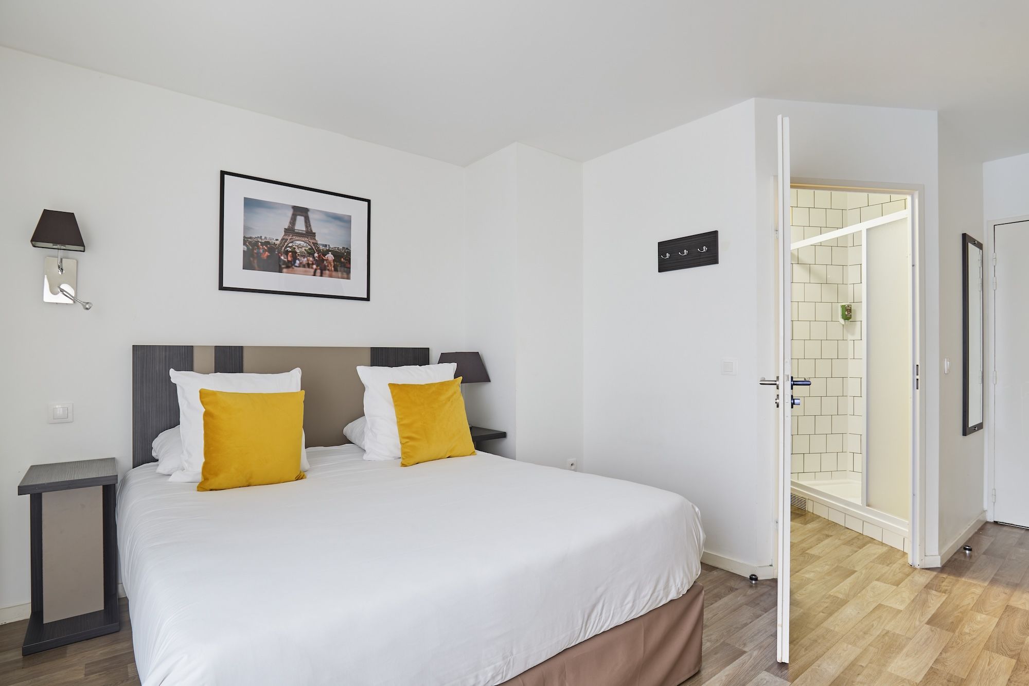 image Relax in a stylish bedroom setup, where soft yellow accents on the pillows enhance the comfort of your king-sized bed, just steps away from the shower.