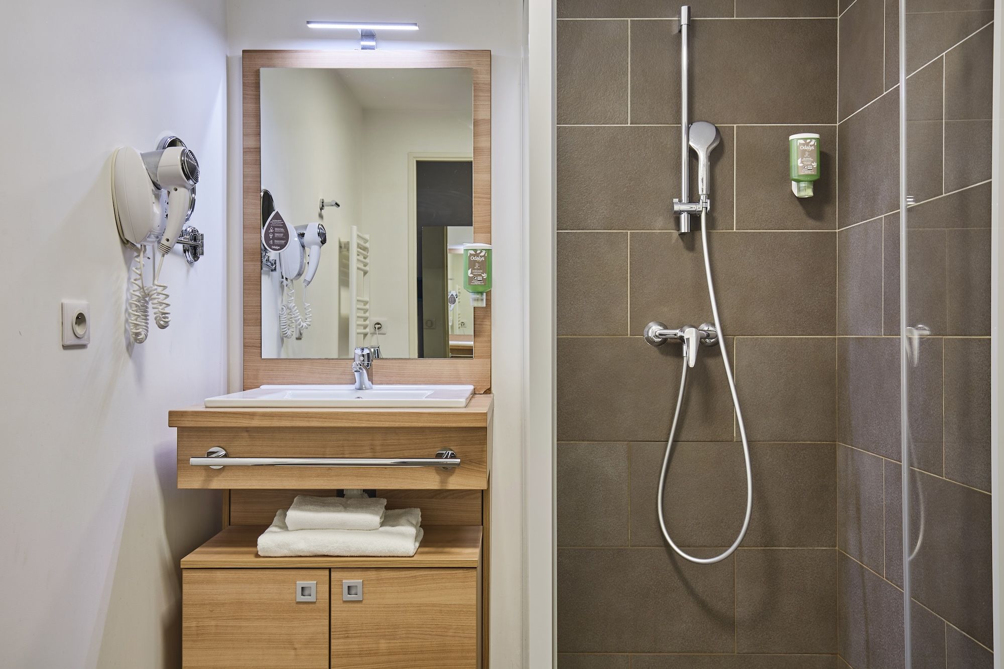 image The well-appointed bathroom features a modern design with wooden cabinetry, a large mirror, and a spacious shower area.