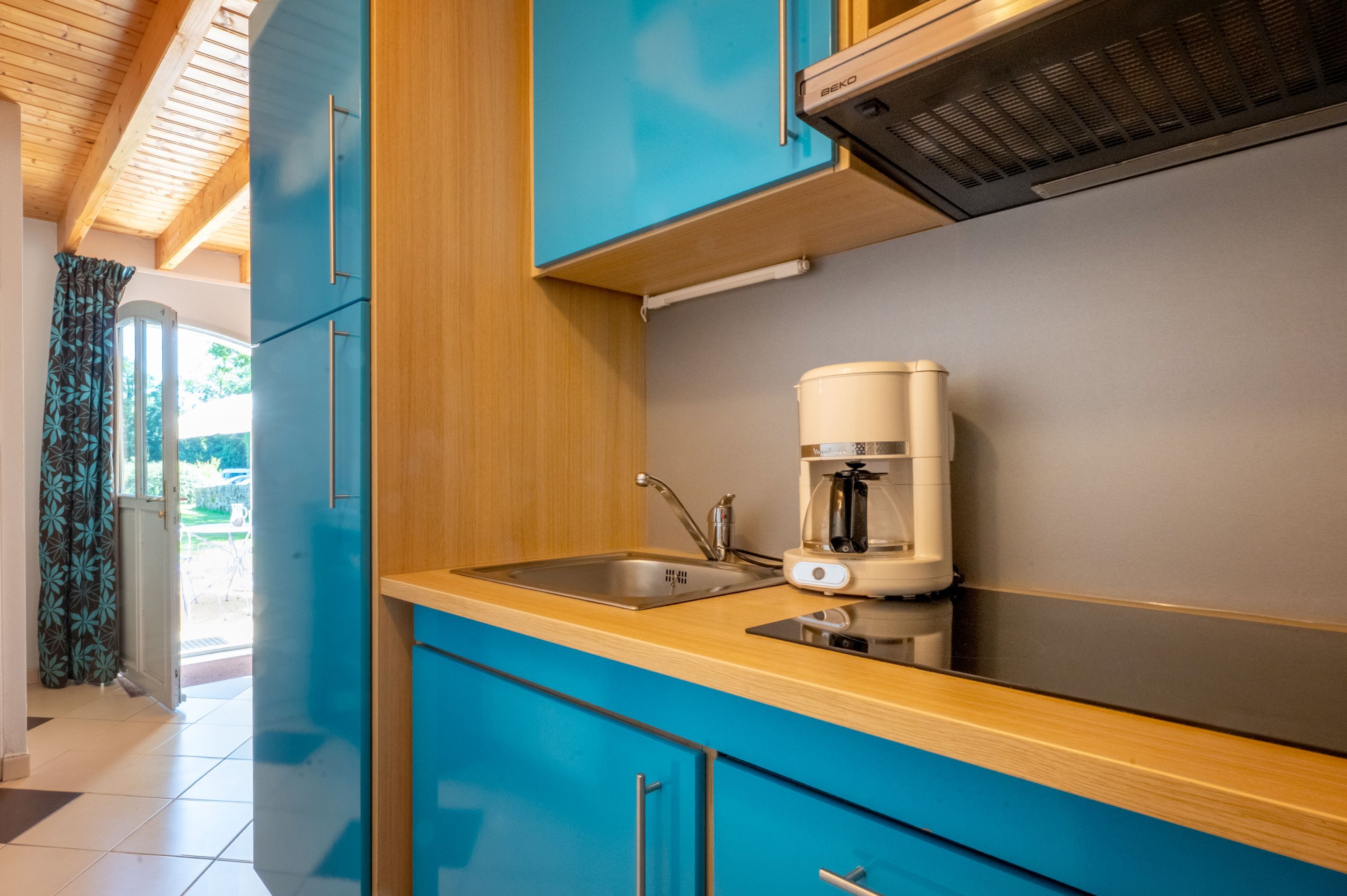 image Blue cabinetry lines the kitchen, with a coffee maker set up for the morning brew.