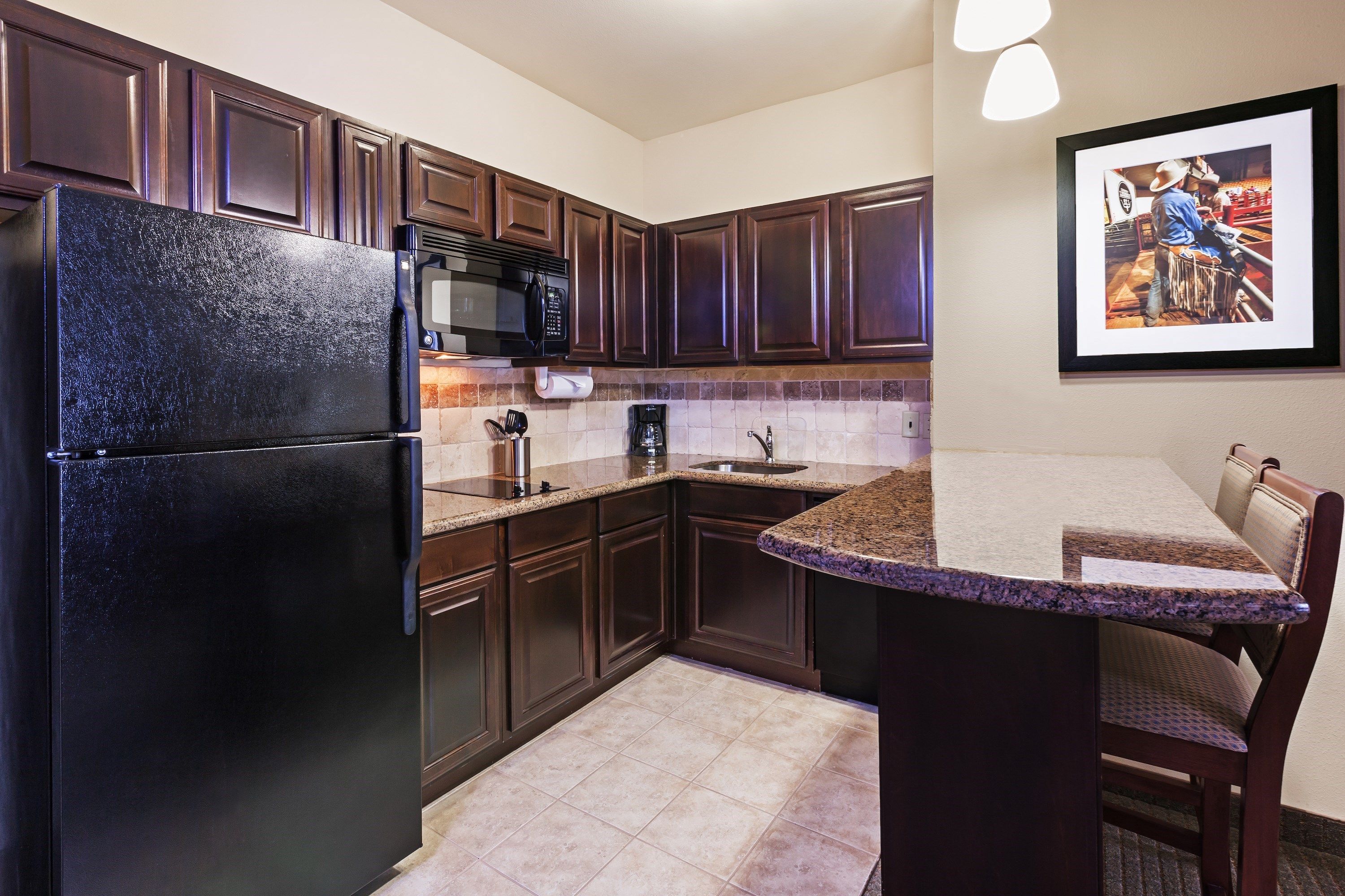 image Modern kitchen featuring dark cabinetry and granite countertops.